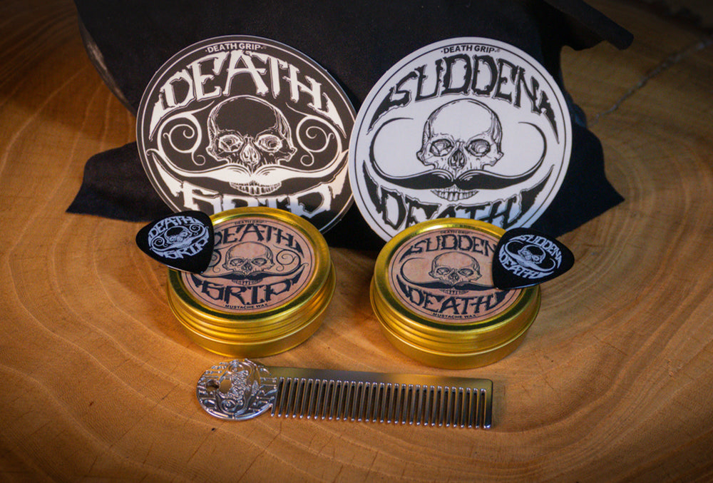 Death Grip mustache wax gift set with wax tins, metal comb, and picks displayed on wooden surface